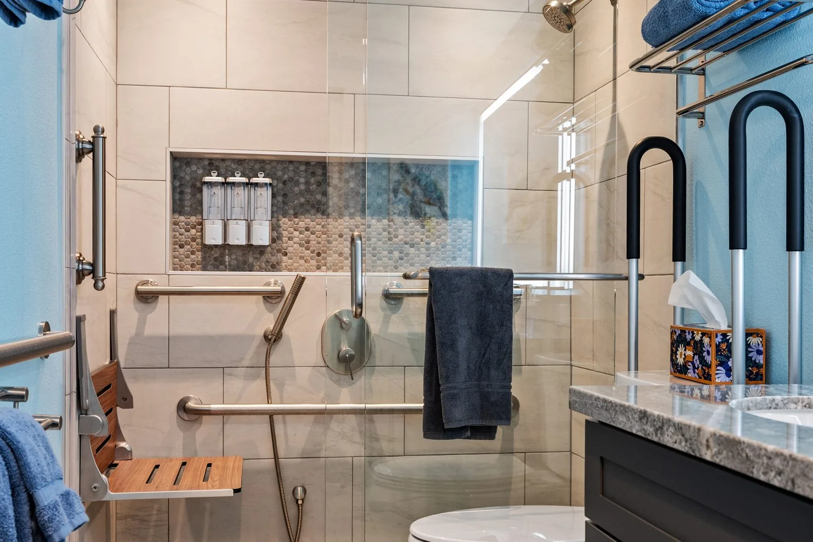 Zero-threshold walk-in shower with teak seat, grab bars, niche, and handheld wand