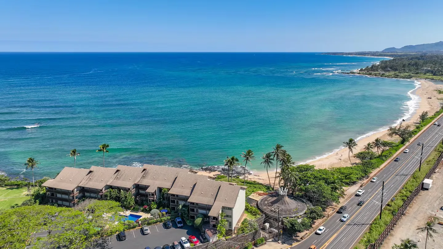 Aerial view of Wailua Bay View #102 — the oceanfront building above a wide turquoise bay on Kauai's East Shore