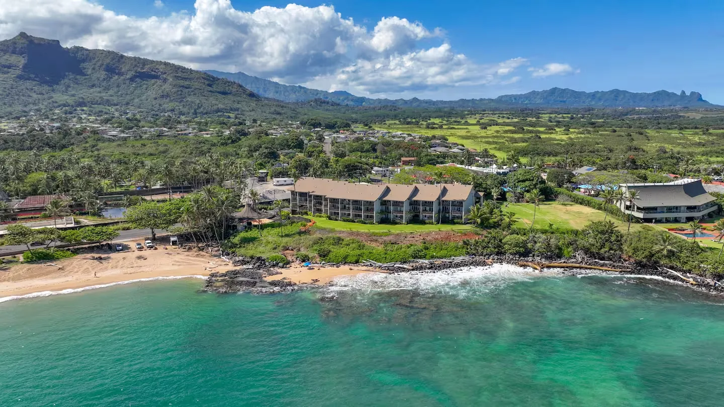Aerial of Wailua Bay View #102 with the Sleeping Giant mountain ridge rising behind the coast