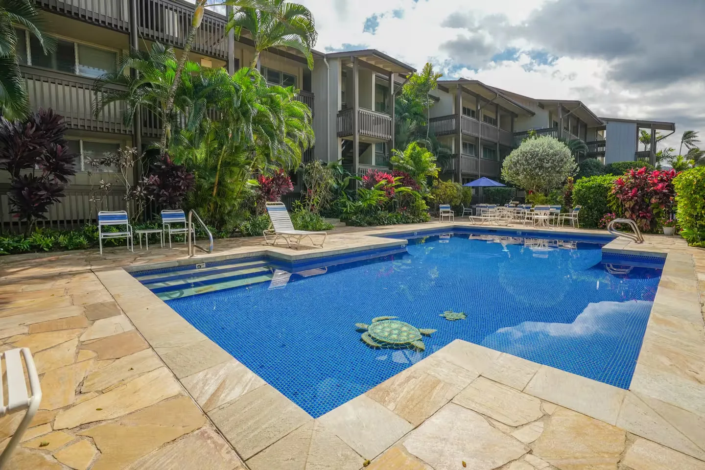 Resort pool with a honu (sea turtle) mosaic, flagstone deck, and lounge chairs
